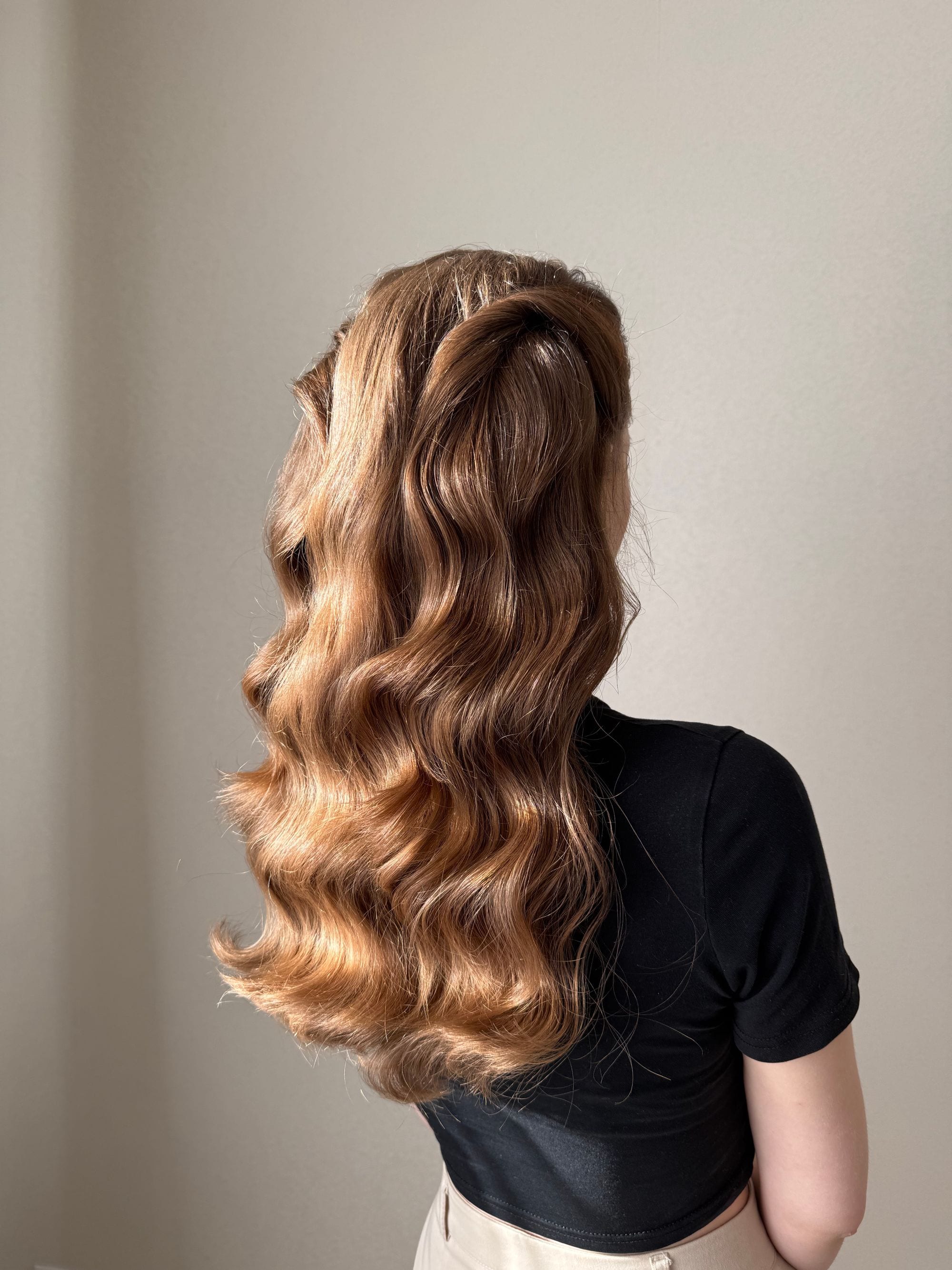 Long, glossy waves seen from behind against a warm neutral wall