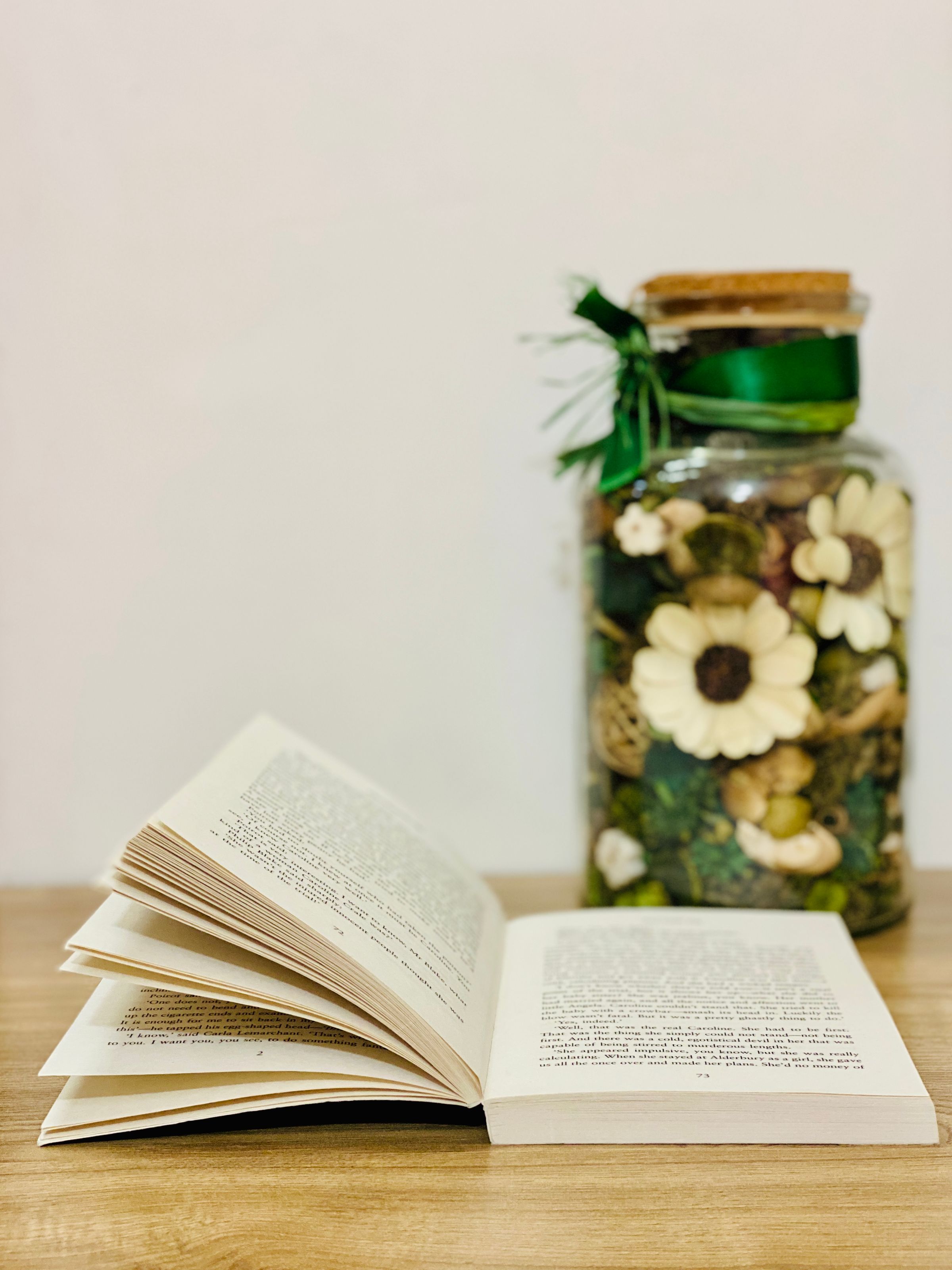 An open book beside a jar of flowers in warm daylight
