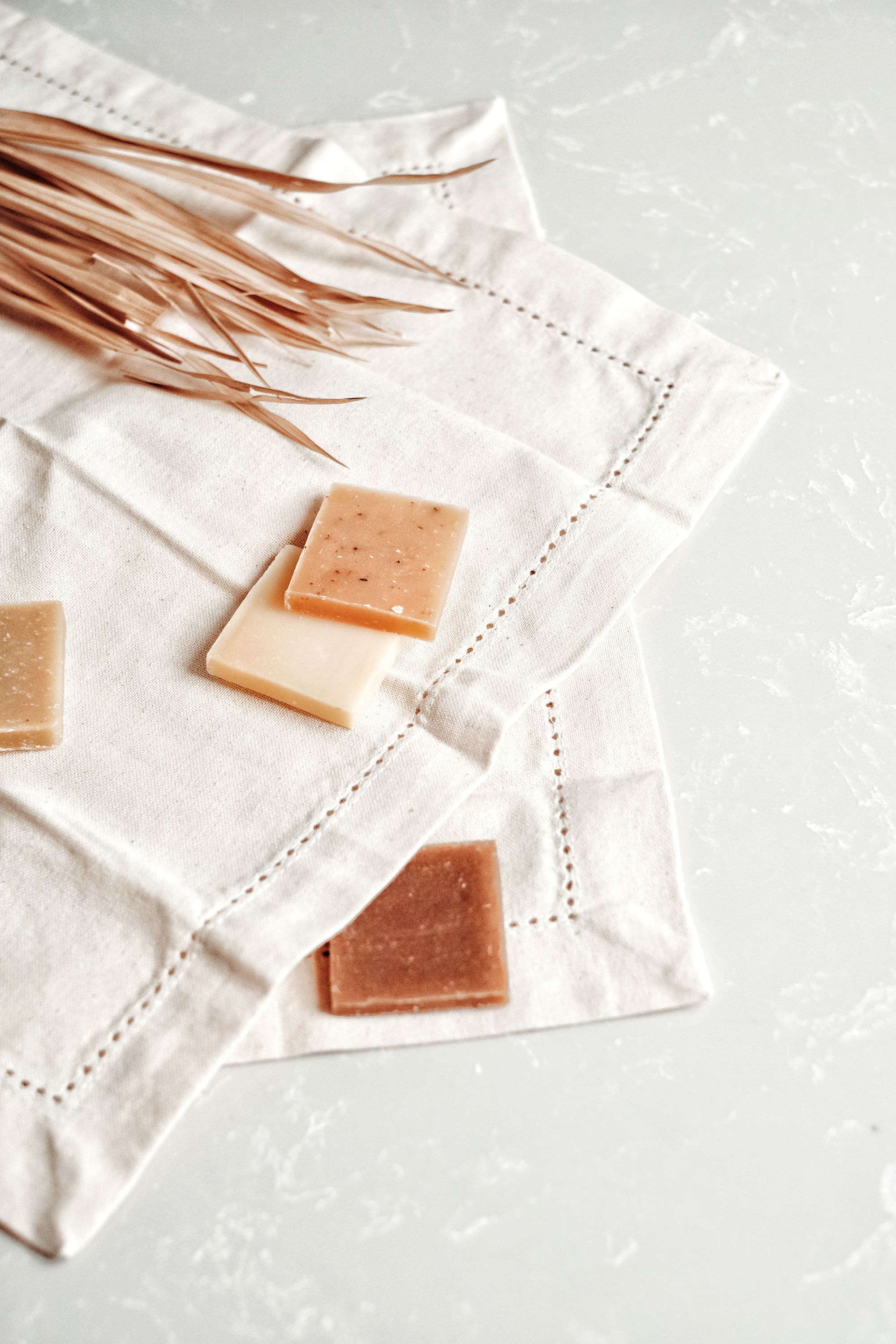 Amber botanical soap bars laid out on white linen with dried grasses